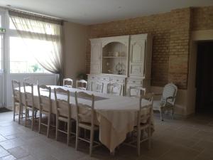 una sala da pranzo con tavolo e sedie bianchi di La Grange Champenoise ad Auménancourt-le-Grand