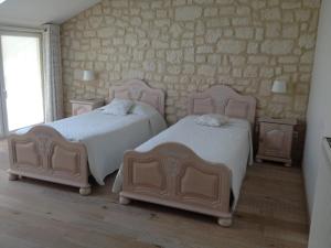 een slaapkamer met 2 bedden en een stenen muur bij La Grange Champenoise in Auménancourt-le-Grand