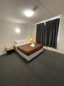 - une chambre avec un grand lit et une fenêtre dans l'établissement Parkside Inn Motel, à Melbourne