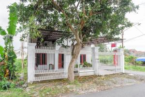 a white fence with a tree in front of a house at RedDoorz Syariah near UMS Solo in Solo
