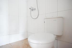 bagno bianco con servizi igienici e doccia di RedDoorz Syariah near UMS Solo a Solo