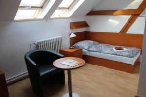 a bedroom with a bed and a chair and a table at Ubytování Na špejcharu, Želevčice in Slaný