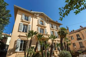 a building with palm trees in front of it at AC-Free Parking - Contemporary 4 Bedroom Villa Apartment in Cannes