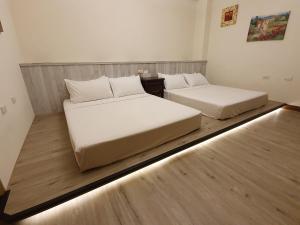 two beds in a room with wood floors at 涵庭民宿 in Hualien City