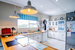 a large kitchen with white cabinets and a large window at Die Strandhuis - Stilbaai in Stilbaai