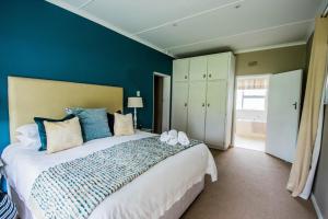 1 dormitorio con 1 cama grande y paredes azules en Die Strandhuis - Stilbaai, en Stilbaai