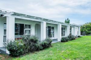 a white house with bushes in the yard at Die Strandhuis - Stilbaai in Stilbaai