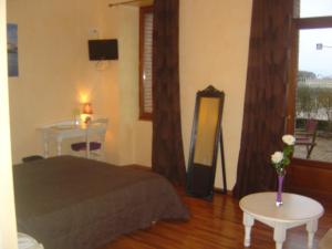 a bedroom with a bed and a table and a mirror at Logis Hôtel Les 3B in Nouilhan