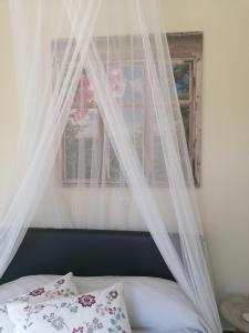 1 cama con cortinas blancas y ventana en LAOUTARIS INN, en Panayia