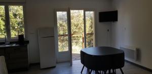 uma cozinha com uma mesa, um frigorífico e uma janela em La petite étape em Duilhac