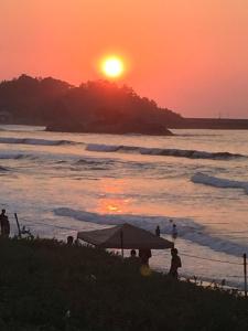 people standing on the beach watching the sunset at Iwamino Oyado lucere in Uradome