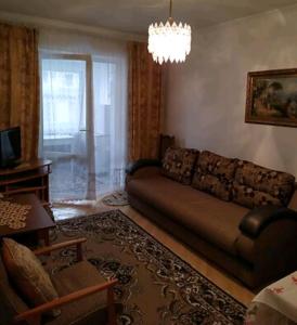 een woonkamer met een bank en een kroonluchter bij 2 кімнатна квартира Трускавець,поруч центр та Дельфінарій in Truskavets