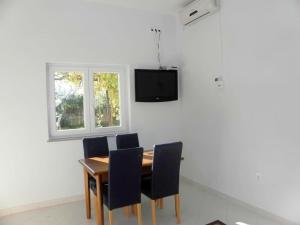 einen Esstisch mit Stühlen und einen TV an der Wand in der Unterkunft Apartment in Duce with Terrace, Air conditioning, Wi-Fi, Washing machine (4166-6) in Duće