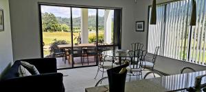 a room with a balcony with a table and chairs at Augusta Grand Pauanui, a Golfers Dream House in Pauanui