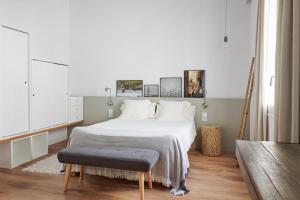 1 dormitorio con cama blanca grande y banco en Mon restaurant & fonda, en Ciutadella