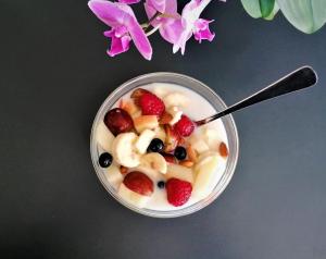 a bowl of yogurt with fruit and a spoon at Bed & Healing in Undløse