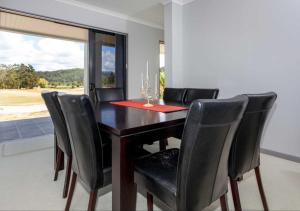 a dining room table with black chairs and a window at Augusta Grand Pauanui, a Golfers Dream House in Pauanui +20 photos