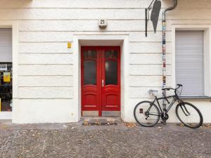 ベルリンにあるApartments Berlin Niederbarnimstraßeの赤いドアの前に駐輪した自転車
