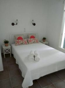Un dormitorio con una cama blanca con toallas. en Chez Semiramis Sunrise Serifos 11 persons, en Rámos