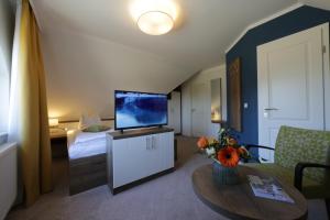 ein Wohnzimmer mit einem TV und ein Zimmer mit einem Bett in der Unterkunft Gasthof "to`n Eikbom" in Dargen