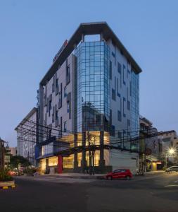duży szklany budynek z czerwonym samochodem przed nim w obiekcie Hotel 88 Blok M Jakarta By WH w Dżakarcie