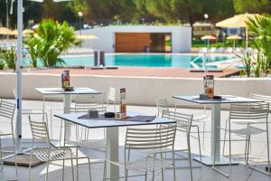 two tables and chairs next to a swimming pool at Camping Stella Maris Mobile Homes in Umag