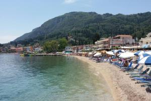 a beach with many chairs and umbrellas and the water at Nafsika House Benitses in Benitses