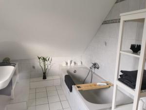 ein weißes Badezimmer mit einer Badewanne und einem Waschbecken in der Unterkunft Appartements Papillon in Gevelsberg