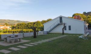 a white building with a picnic table and a bench at Casa do Carvalho - Ponte de Lima in Ponte de Lima