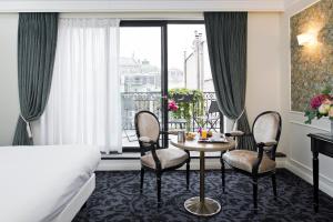 una camera d'albergo con tavolo, sedie e letto di Hôtel Saint-Pétersbourg Opéra & Spa a Parigi