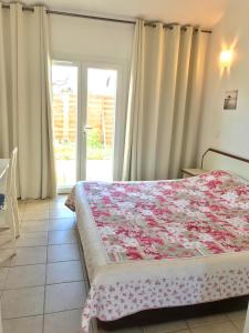 a bedroom with a bed with a flowered blanket on it at Le Maset in Saintes-Maries-de-la-Mer