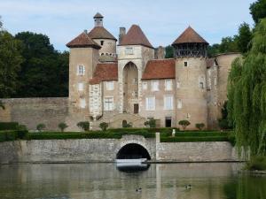 a castle with a bridge and a boat in the water at le Chaumois in Saint-Boil
