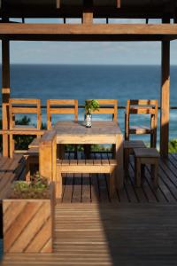 a wooden table and chairs on a deck with the ocean at Aloha 22 in Ponta Mamoli