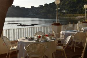 a restaurant with tables and chairs next to a body of water at Hotel Lido Mediterranee in Taormina
