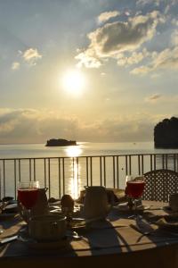 a table with wine glasses on a balcony with the ocean at Hotel Lido Mediterranee in Taormina