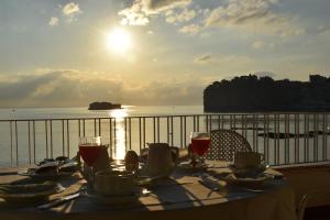 a table with glasses of wine on a balcony with the ocean at Hotel Lido Mediterranee in Taormina