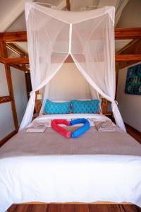 a bed with a canopy with two slippers on it at Aloha 22 in Ponta Mamoli