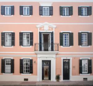 un bâtiment rose avec des volets noirs et un balcon dans l'établissement Can Alberti 1740 Boutique Hotel, à Port Mahon