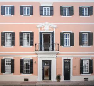 Edificio rosa con persianas negras y balcón en Can Alberti 1740 Boutique Hotel, en Mahón