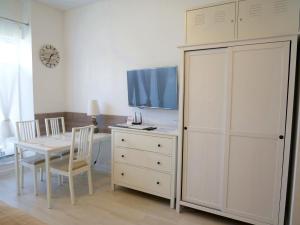 a room with a table and a tv and a white cabinet at Trzy Wyspy Apartments - Aquamarina in Świnoujście