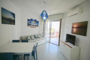 ein Wohnzimmer mit einem Sofa, einem Tisch und einem TV in der Unterkunft BA - Cristallo - Sea View - in Lignano Sabbiadoro