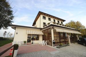 une maison blanche avec une terrasse et des chaises blanches dans l'établissement Terzo Bacino, à San Michele al Tagliamento