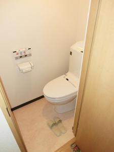 a bathroom with a toilet and a pair of slippers at BK Hotel & Weekly in Wakayama