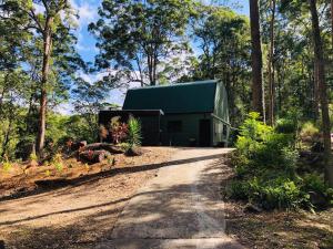 LandsboroughLAKE VIEW CHALET Australia Zoo close by的树林里有绿色屋顶的绿色建筑