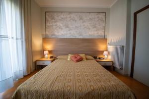 a bedroom with a large bed with two tables and two lamps at Hotel Venezuela in Montesano sulla Marcellana