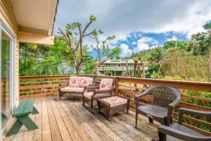 una terraza de madera con sillas y mesa en Moloa'a Bay Cottage, en Anahola