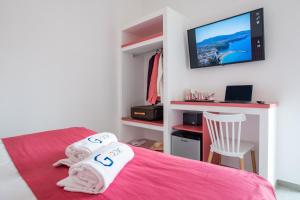 a bedroom with a pink bed with a tv on the wall at Al Campanile in Sant'Agnello