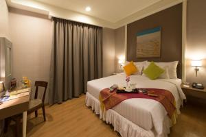 een hotelkamer met een groot bed en een bureau bij Pranaya Boutique Hotel in Serpong