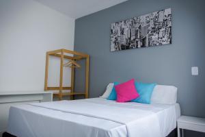 a bedroom with a white bed with a pink and blue pillow at Pousada Maceio Paradise in Maceió