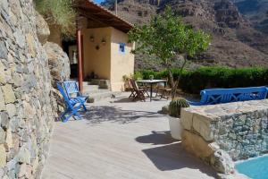 een patio met blauwe stoelen en een tafel en een huis bij Casa con piscina privada en Cercados de Espino in Las Casillas